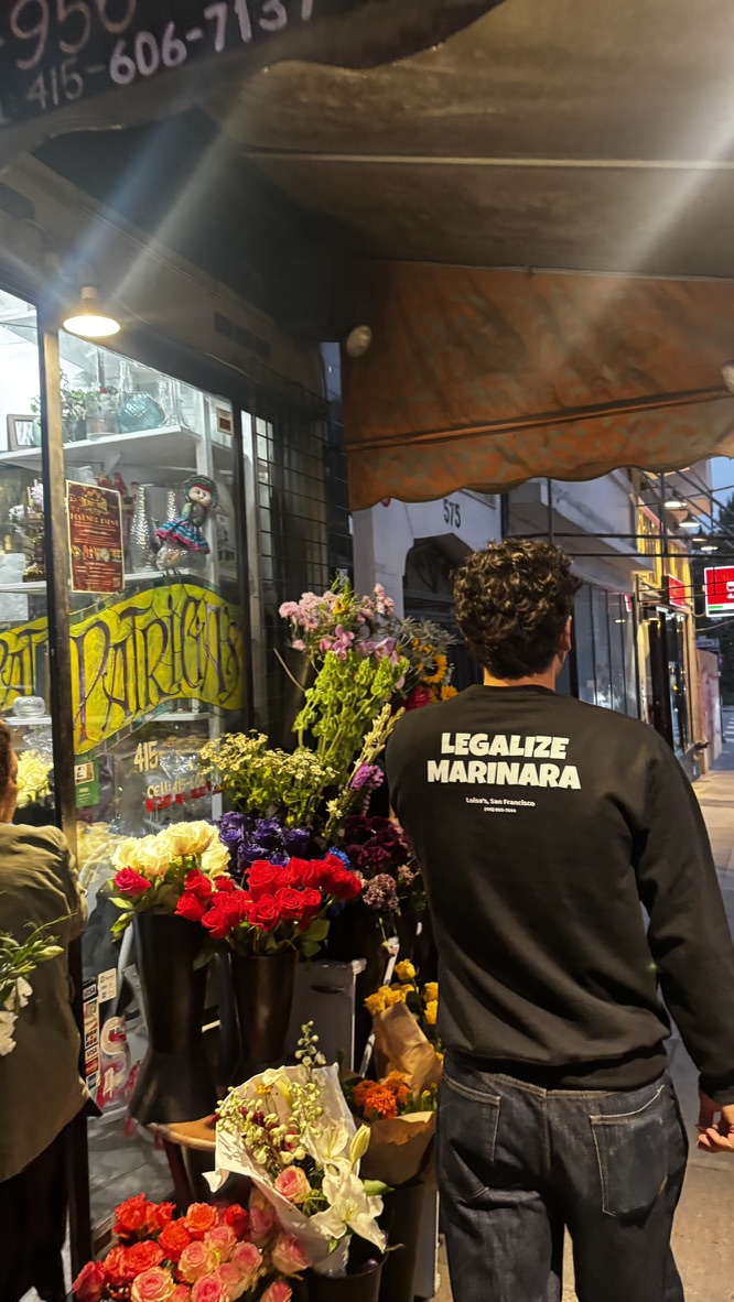 The black crewneck at a flower stand at night